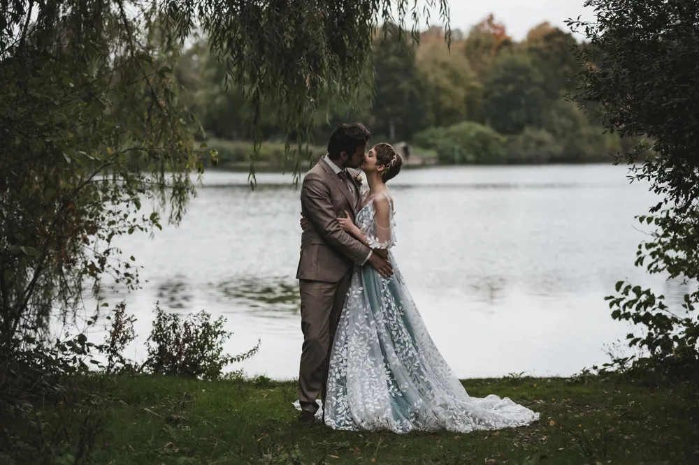 real bride Lauren van der Genugten in een unieke trouwjurk met verfijnde bladerenapplicaties, romantisch moment met haar bruidegom aan het water