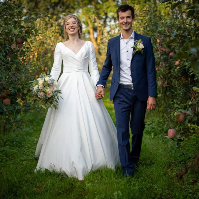 real bride Jessica Blom Aperloo hand in hand met haar partner in een boomgaard, frisse en romantische setting