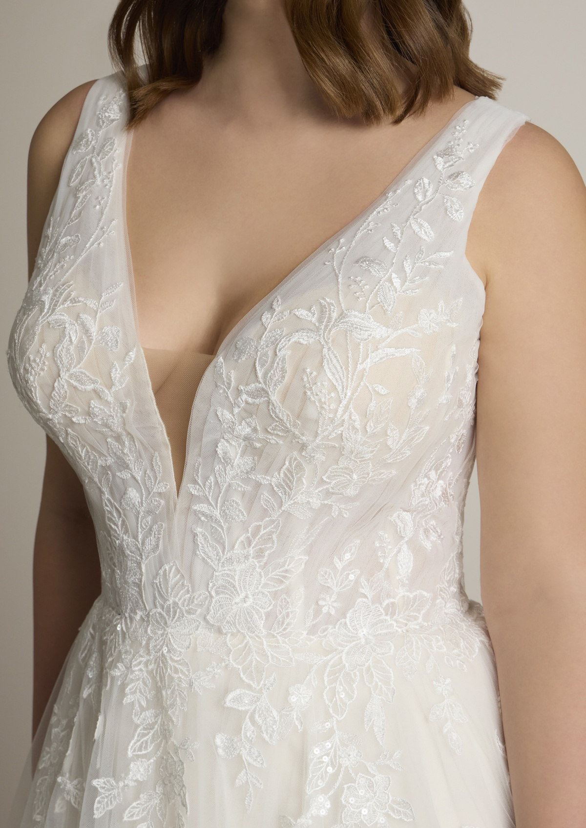 Trouwjurk met V-hals Sugon van Ladybird. Close-up van het lijfje met bloemenkant en doorlopende kanten schouderbandjes.