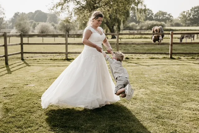 real bride anouk coopmans in een romantische a-lijn trouwjurk spelend met haar kindje in een landelijke setting
